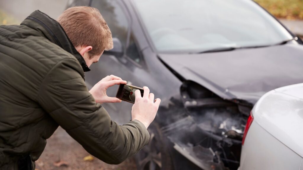 Un hombre tomando fotos después de un choque entre carros.