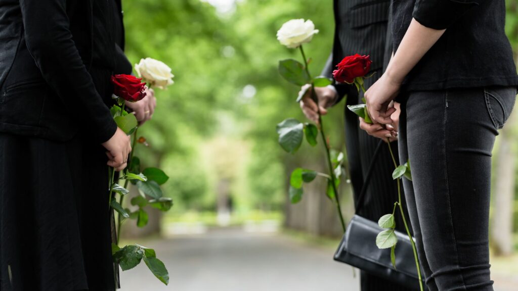 Gente vestida de negro y con rosas en la mano listas para un funeral.