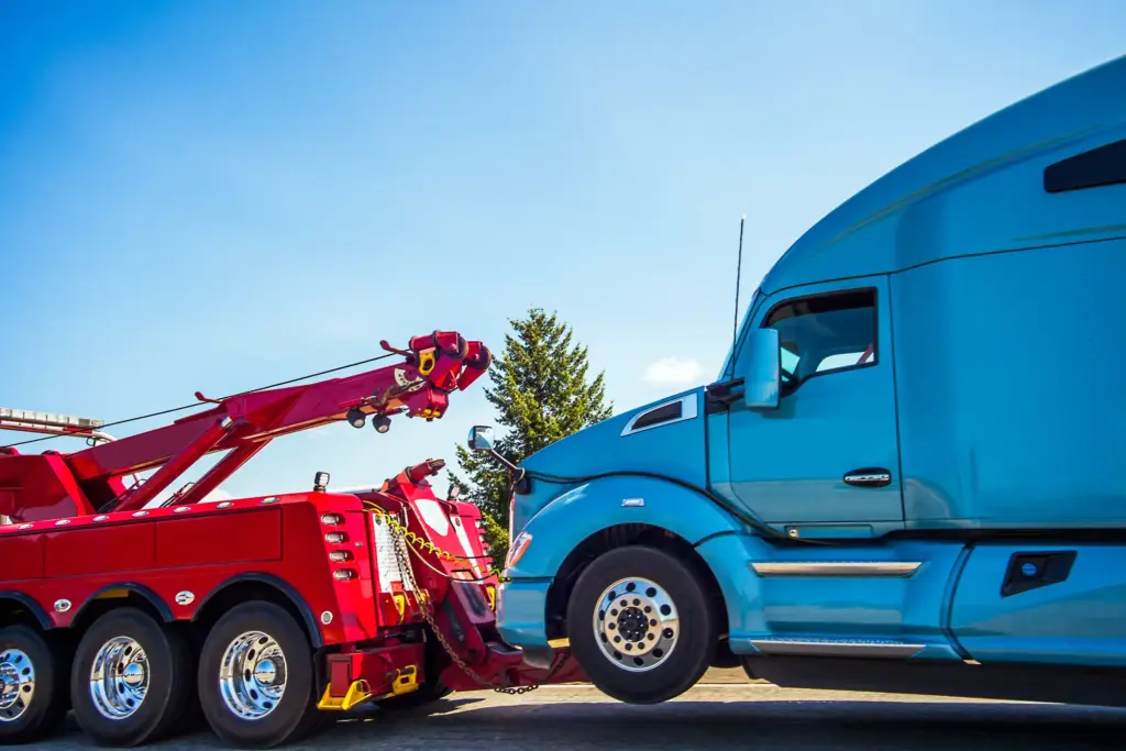 A red tow truck pulling a blue semi truck.