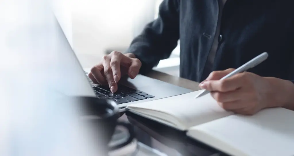 A man on a laptop taking notes.